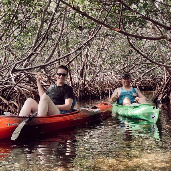 a man and a woman kayaking in mangroves